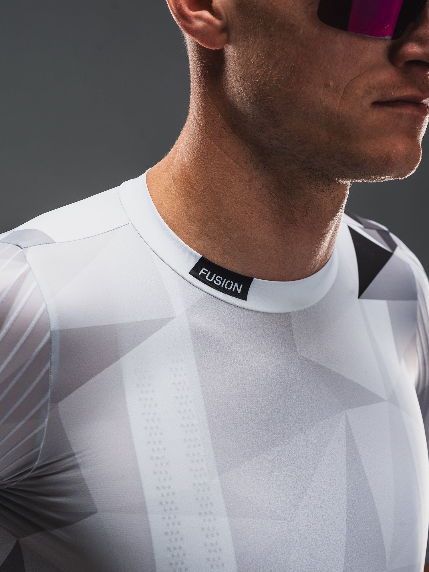 Close-up of a person wearing a white cycle jersey with 'Fusion' branding on a dark background