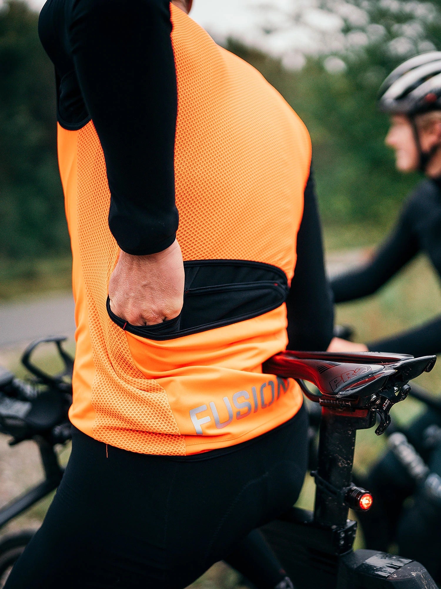 FUSION Tempo! Pro cycle jacket in neon orange showing easy access to jersey pockets